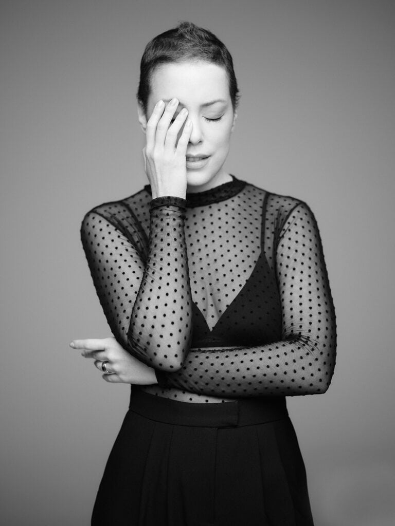 Moda feminina, ensaio de foto preto e branco, mulher com saia preta e blusa de tule com poás, expressão pensativa, estética sofisticada, estilo elegante, sessão de fotos fashion, beleza, glamour, estilismo.