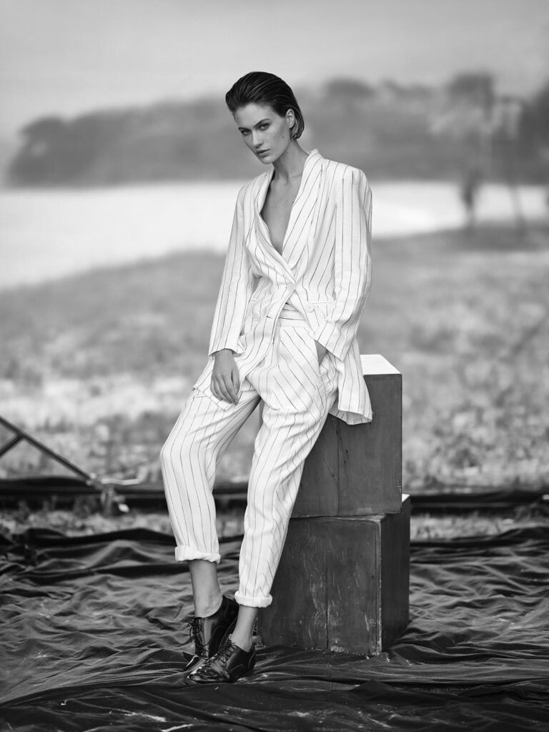 Vestido de alfaiataria listrado em branco e preto em efeito black and white, modelo com cabelo estiloso e pose elegante, na sessão de fotos da Tya Ro Studio.