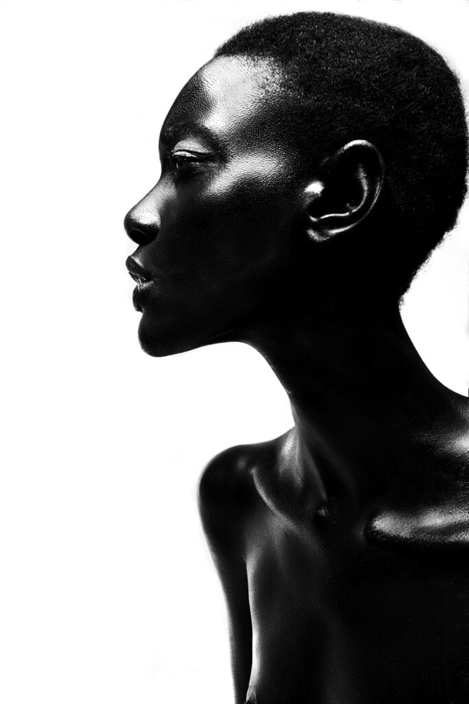 Pele negra maquiada, retrato artístico de mulher com beleza afro, fotografia em preto e branco, arte de destaque na fotografia de moda e beleza, studio de fotos profissional.