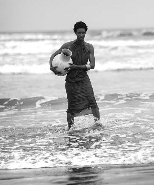Urna de cerâmica sendo segurada por uma mulher na praia ao pôr do sol, moda praia, fotografia em preto e branco, estética artística, shoot de moda, estilo sofisticado, fotos de moda feminina, verão e estilo, Tyardestúdio.com.br.